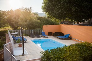Relax by the serene pool surrounded by comfortable lounge chairs and well-manicured hedges.