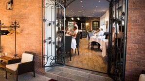 A restaurant with brick walls, a wrought iron gate, and tables set for dining. - Chez La Rose (Juliénas)