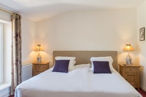 Relax in comfort with a large bed and two bedside tables, each with a decorative lamp.