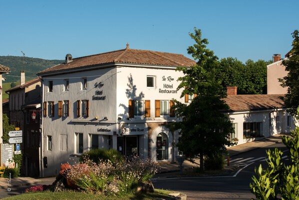 Hotel and restaurant with a traditional European design, featuring a tiled roof and balcony.