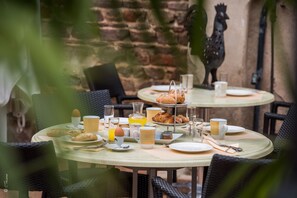 Mesa de café da manhã posta com croissants, ovos e bebidas.