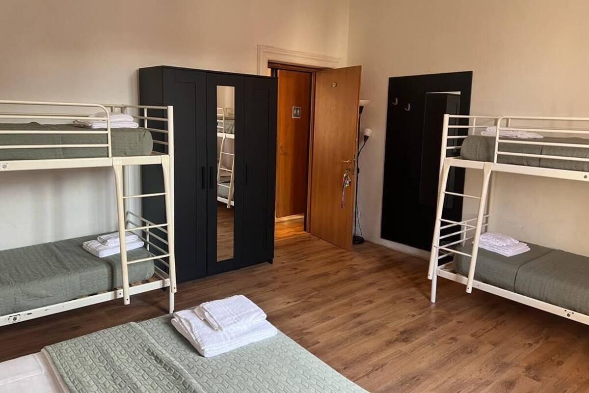 Ein Zimmer mit Etagenbetten, einem Kleiderschrank und einer Tür zu einem weiteren Raum.
