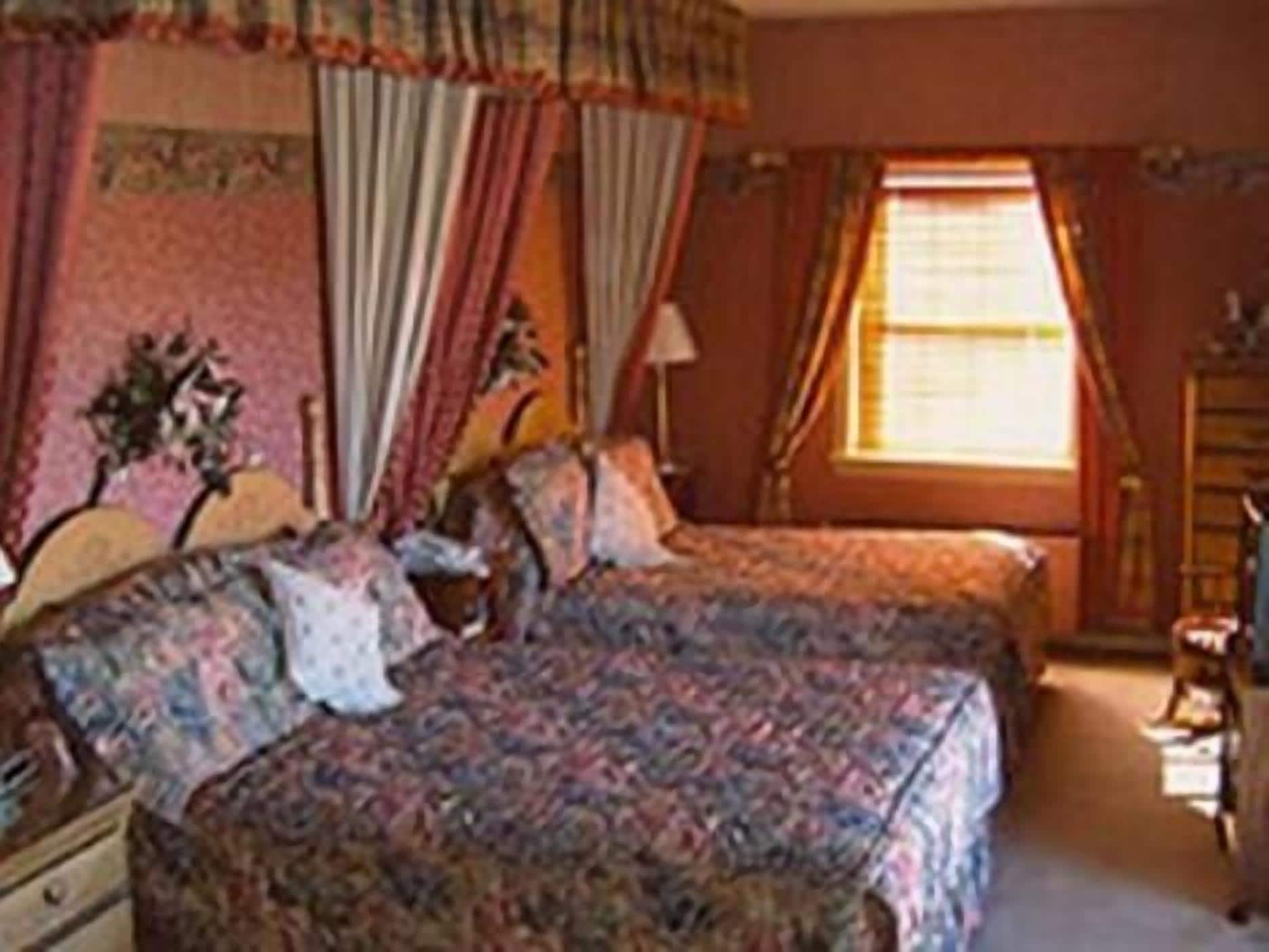 Un dormitorio con dos camas, un aparador y una ventana con cortinas.