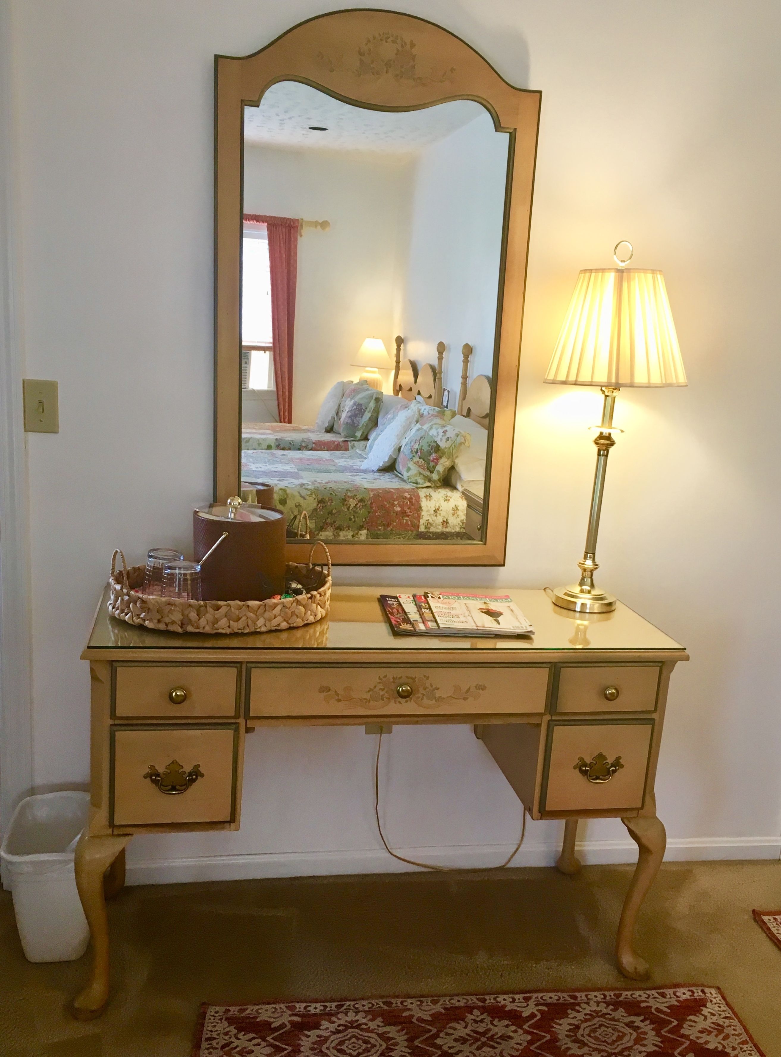A wooden dresser with drawers, a mirror, and a lamp.