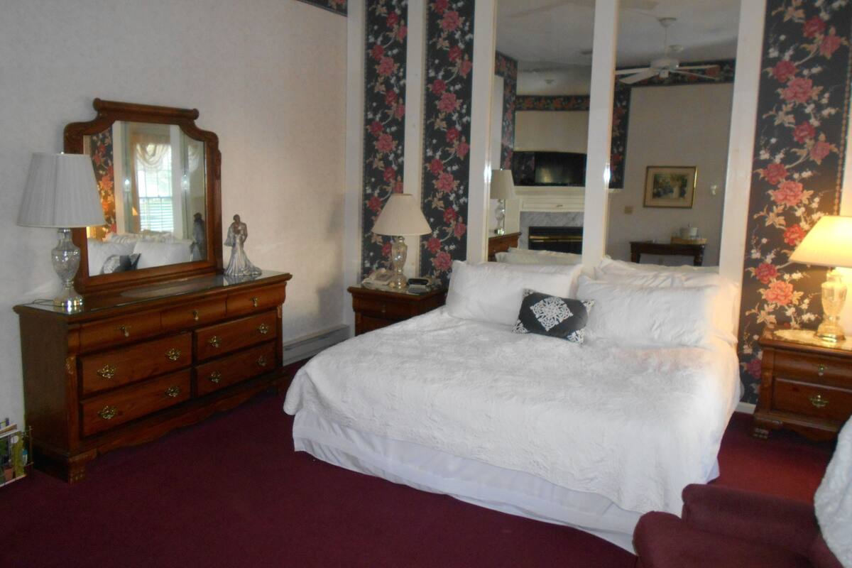A hotel room with a large bed, wooden dresser, and a mirror.