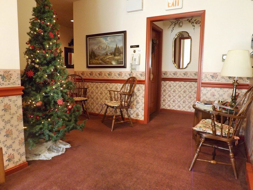 A hotel lobby with a Christmas tree, wooden chairs, a painting on the wall, and a mirror.