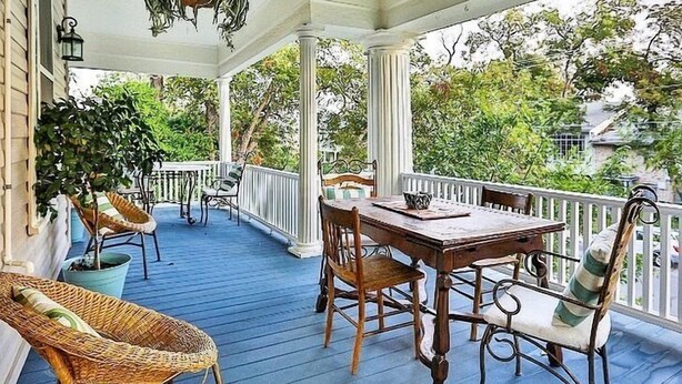 A covered porch with a wooden table and chairs, surrounded by potted plants and a railing. - O'Casey's Boutique Inn (San Antonio)
