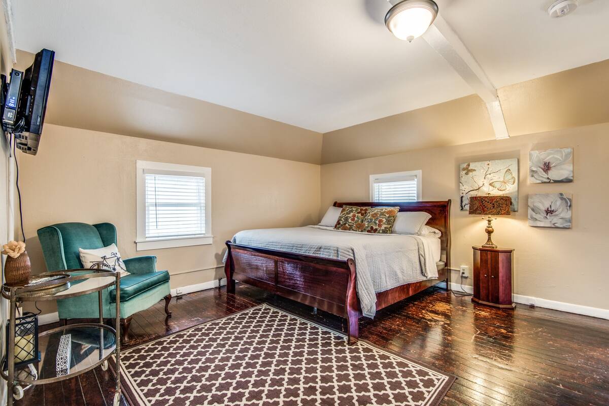 A bedroom with a bed, a chair, a small table, and artwork on the walls.