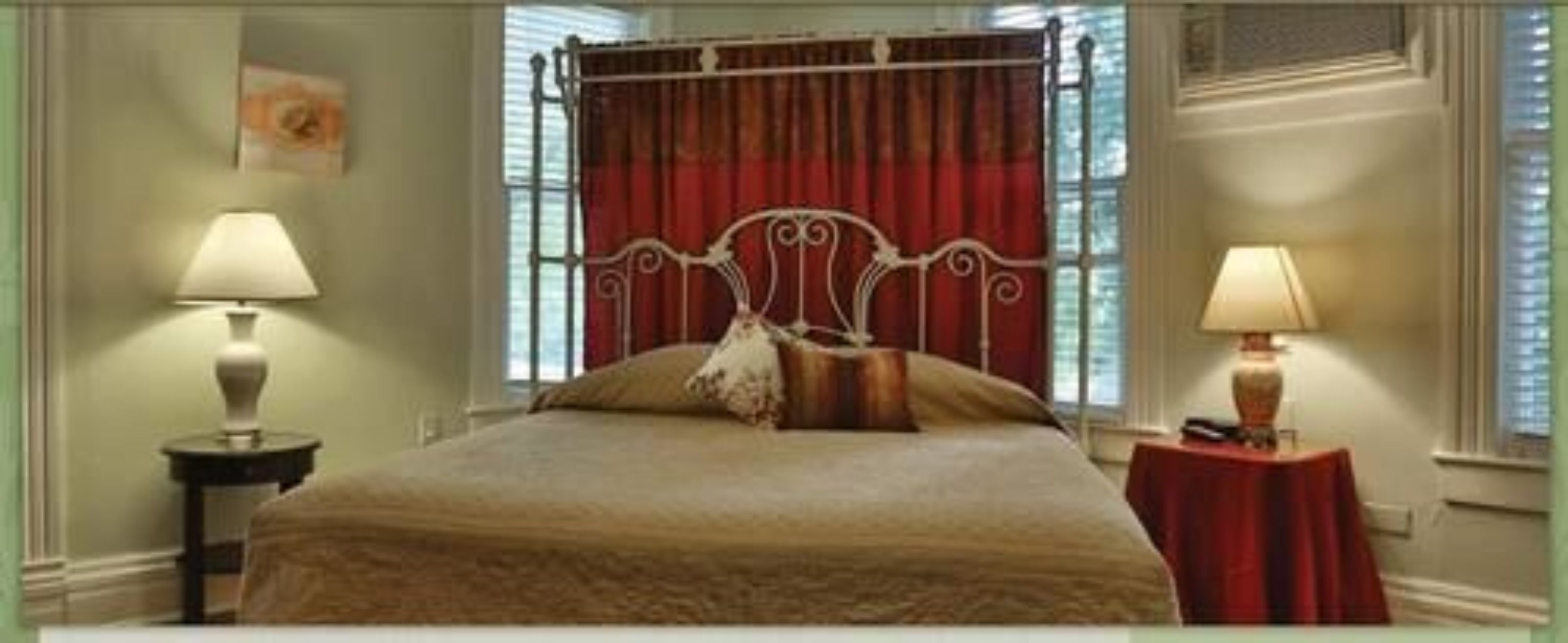 Una camera da letto con un letto a baldacchino, due comodini con lampade e una finestra con tende.