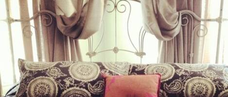 Una cama con una colcha estampada y una almohada roja.