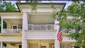 A two-story building with a central entrance, a red door, and an American flag. There are potted plants and a well-maintained lawn in front. - O'Casey's Boutique Inn (San Antonio)