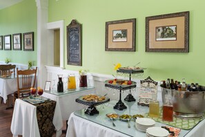 A buffet setup with various food items and drinks, framed pictures on the wall, and a chalkboard sign. - Bayfront Marin House (St. Augustine)