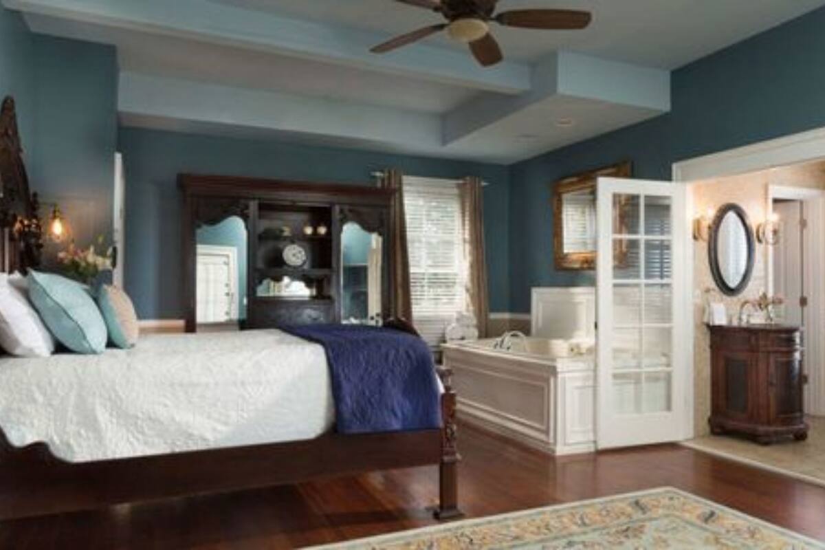 A bedroom with a bed, a dresser, a vanity, and a door leading to another room.