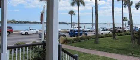 A coastal view with parked cars, palm trees, and a body of water.