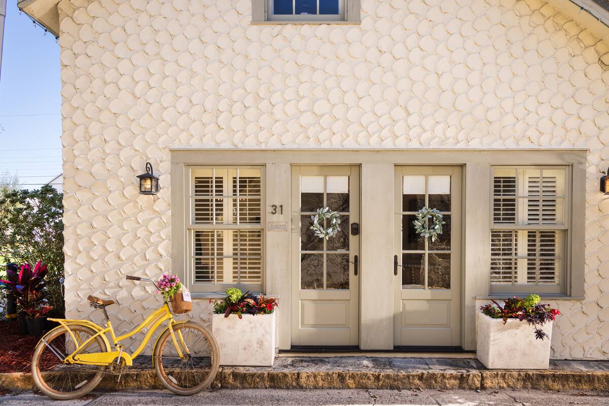A yellow bicycle parked in front of a building with a textured facade, two doors, and a number 31 sign.