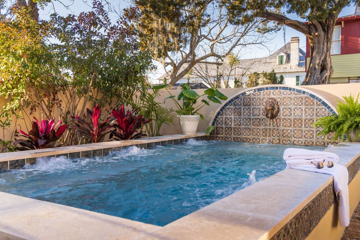 A hot tub with a tiled wall and plants around it.