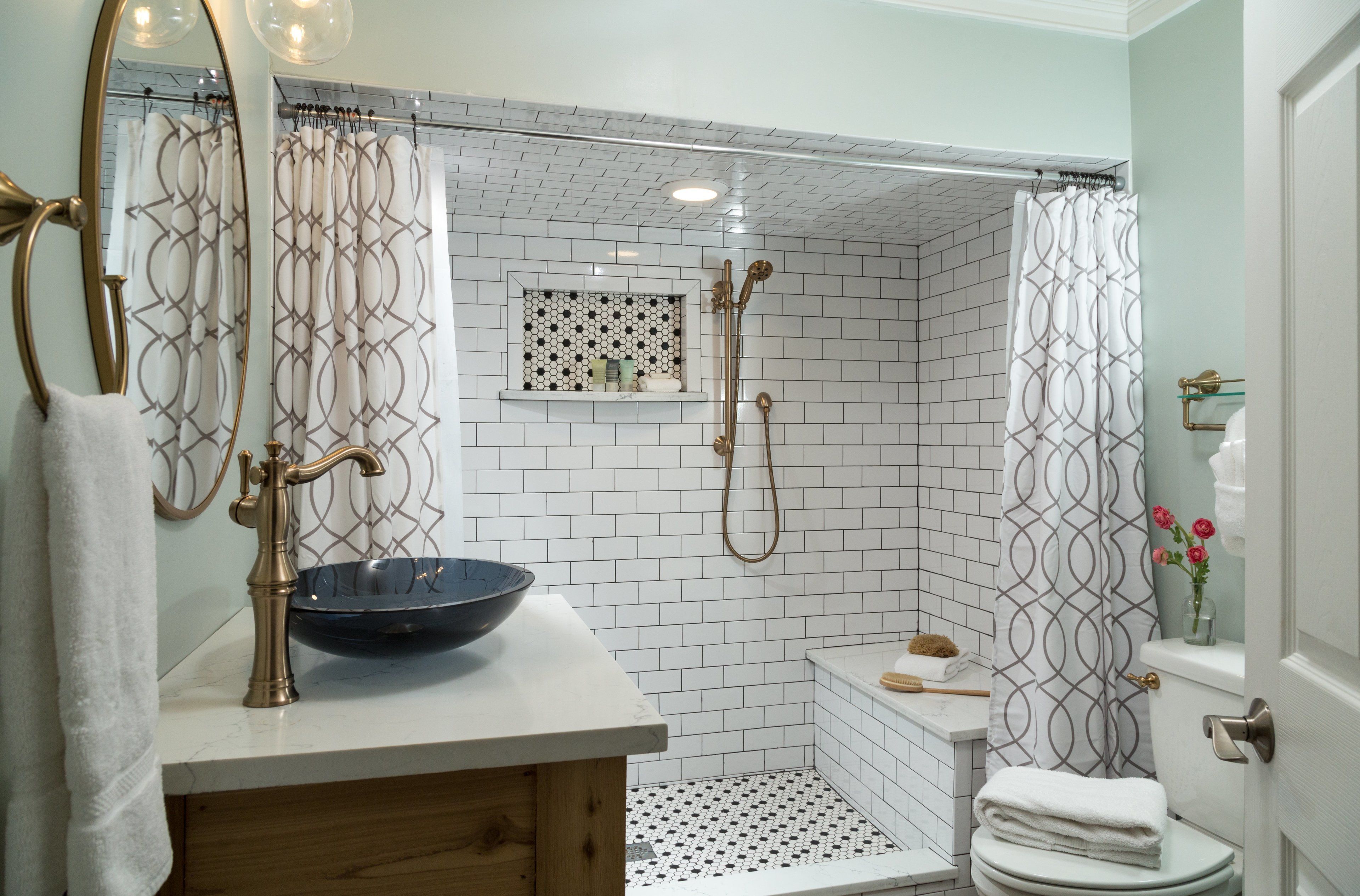 Une salle de bain avec une douche carrelée de carreaux blancs, un lavabo avec un receveur, un miroir et des toilettes.