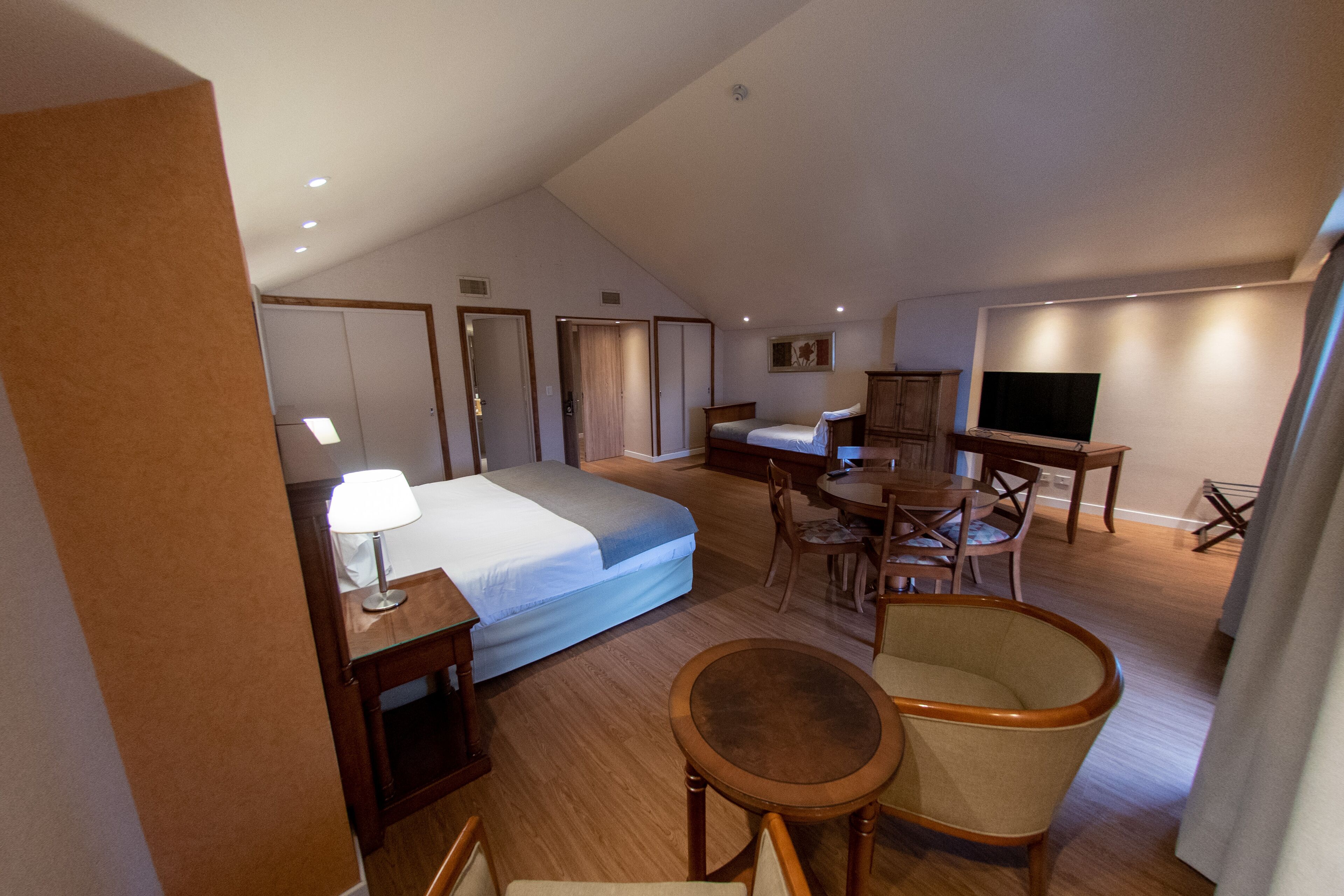 Une chambre d’hôtel comprenant un lit, un bureau, une chaise, un téléviseur et une table à manger.