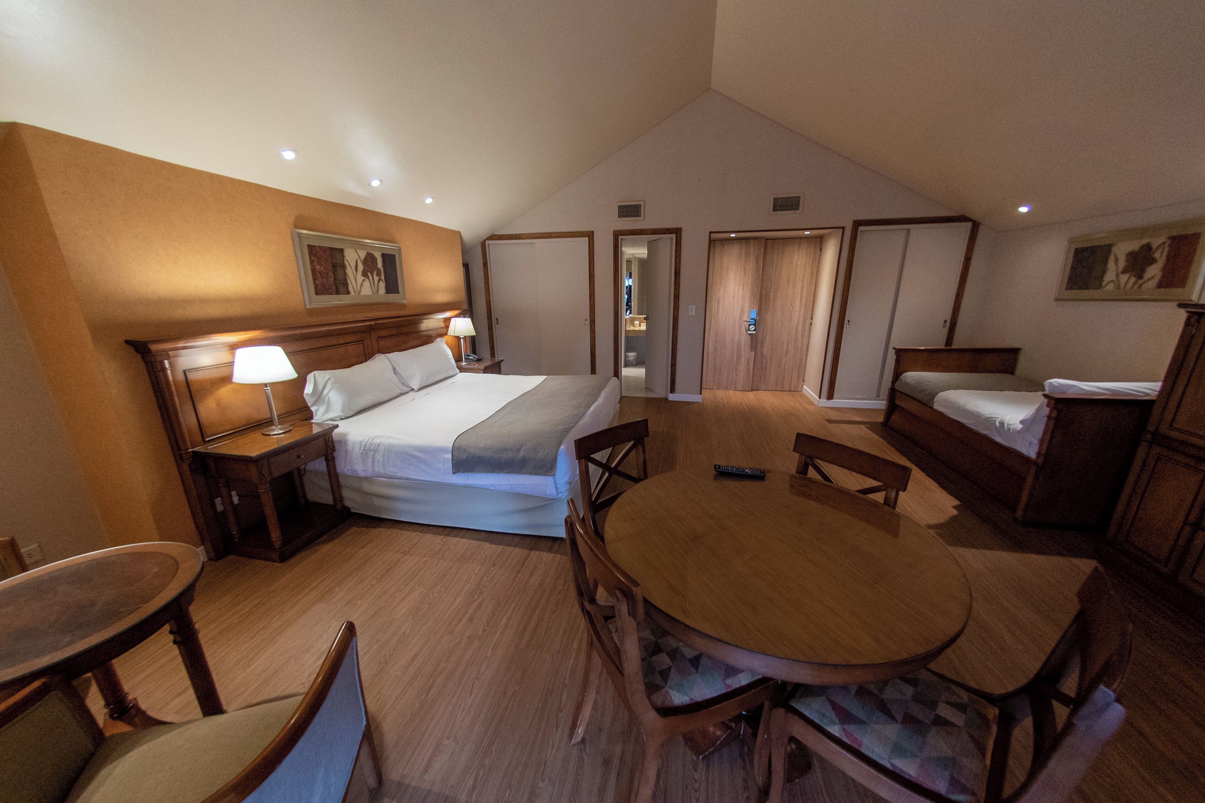 A hotel room with a large bed, bedside tables, a round dining table, and a separate sofa.