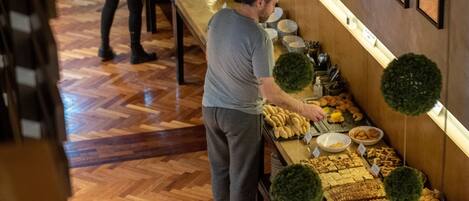A buffet area with a variety of food items and a counter where staff are serving.