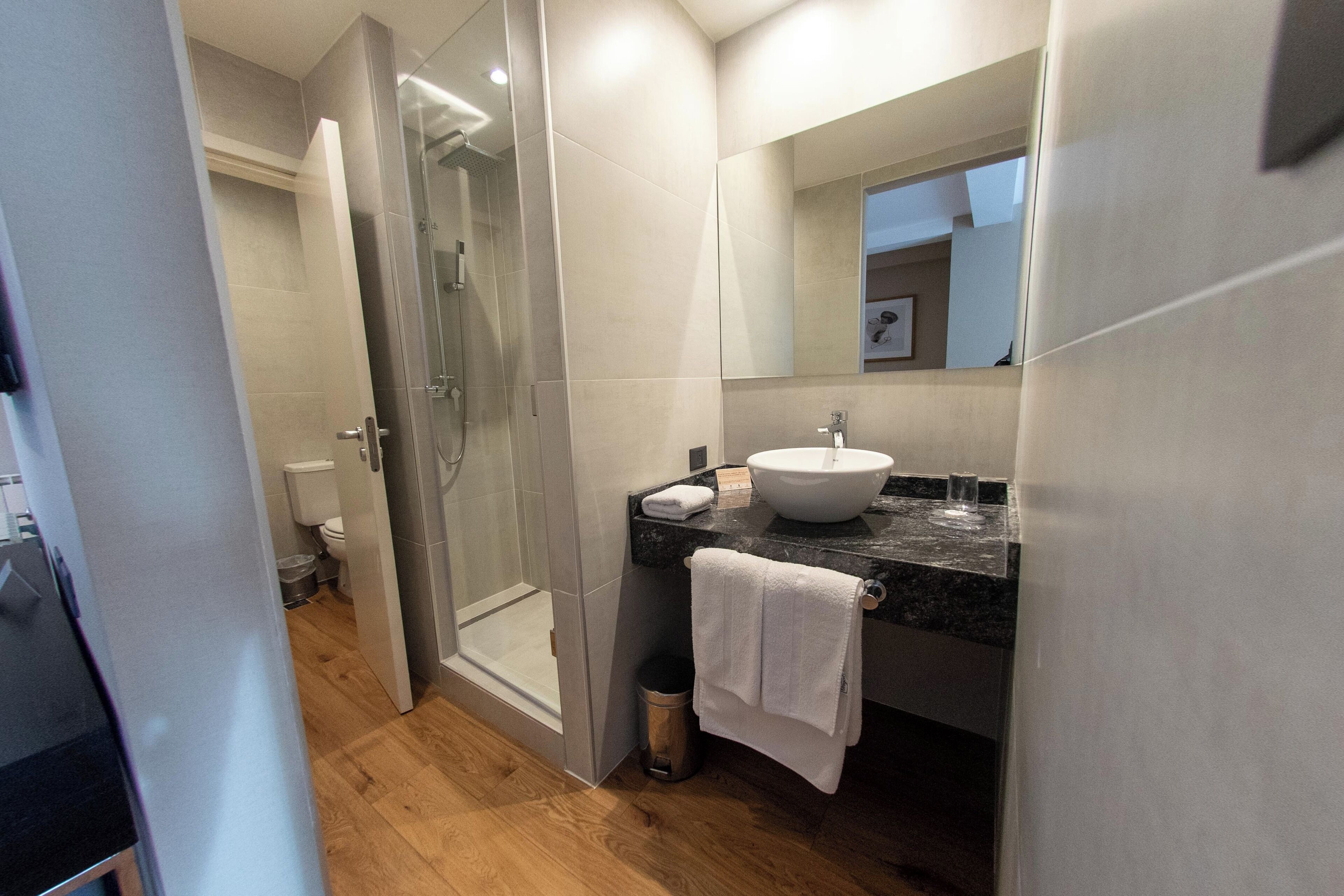 Une salle de bain moderne avec une douche à parois de verre, un lavabo blanc et un grand miroir.