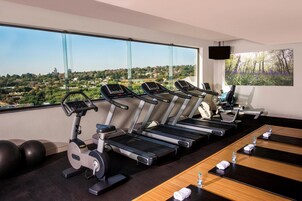 Un gimnasio con cintas de correr, pelotas de ejercicio y vistas panorámicas de la ciudad.