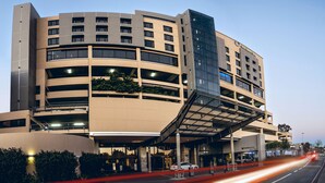 Un hotel de varios pisos con fachada curva, múltiples balcones y un área de entrada cubierta.