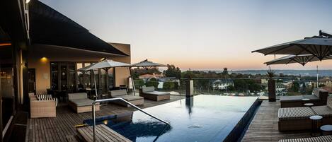 Una piscina al aire libre, sombrillas, sillones reclinables de piscina