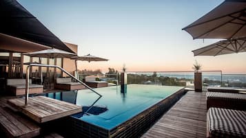 Una piscina al aire libre, sombrillas, sillones reclinables de piscina