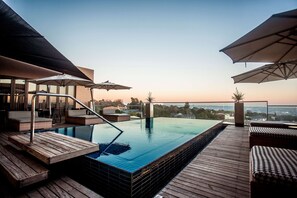 Una piscina al aire libre, sombrillas, tumbonas