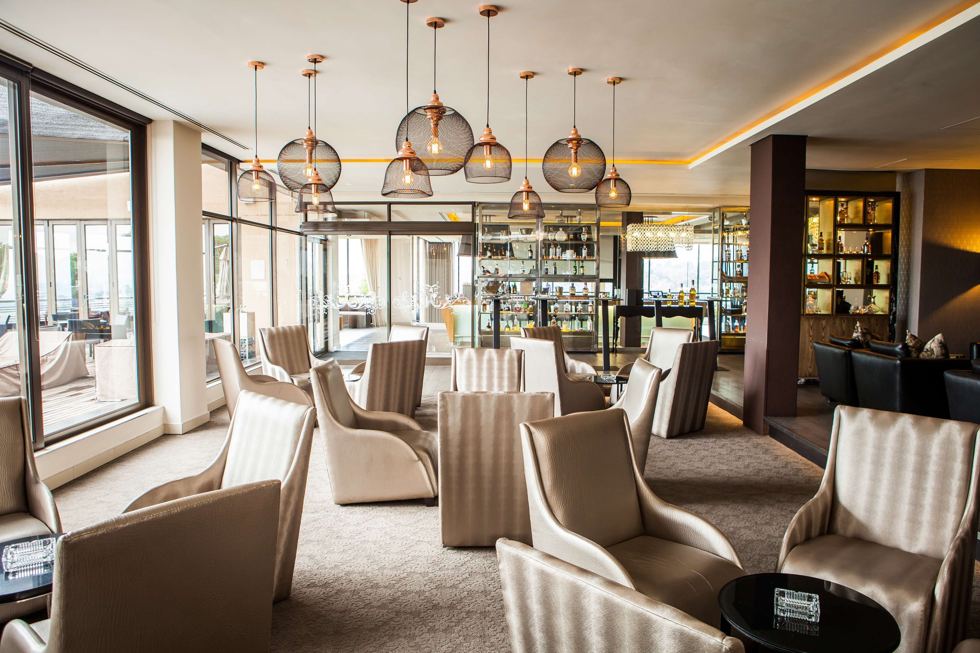 Ein moderner Lounge-Bereich mit Ledersesseln, einer Bar und einem großen Fenster mit Blick.
