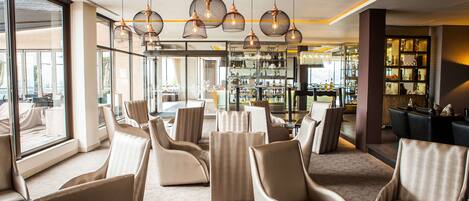 A modern lounge area with leather chairs, a bar, and a large window offering a view.