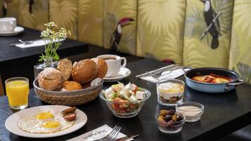 A breakfast setting with eggs, bread, a salad, and a pan of food on a table.