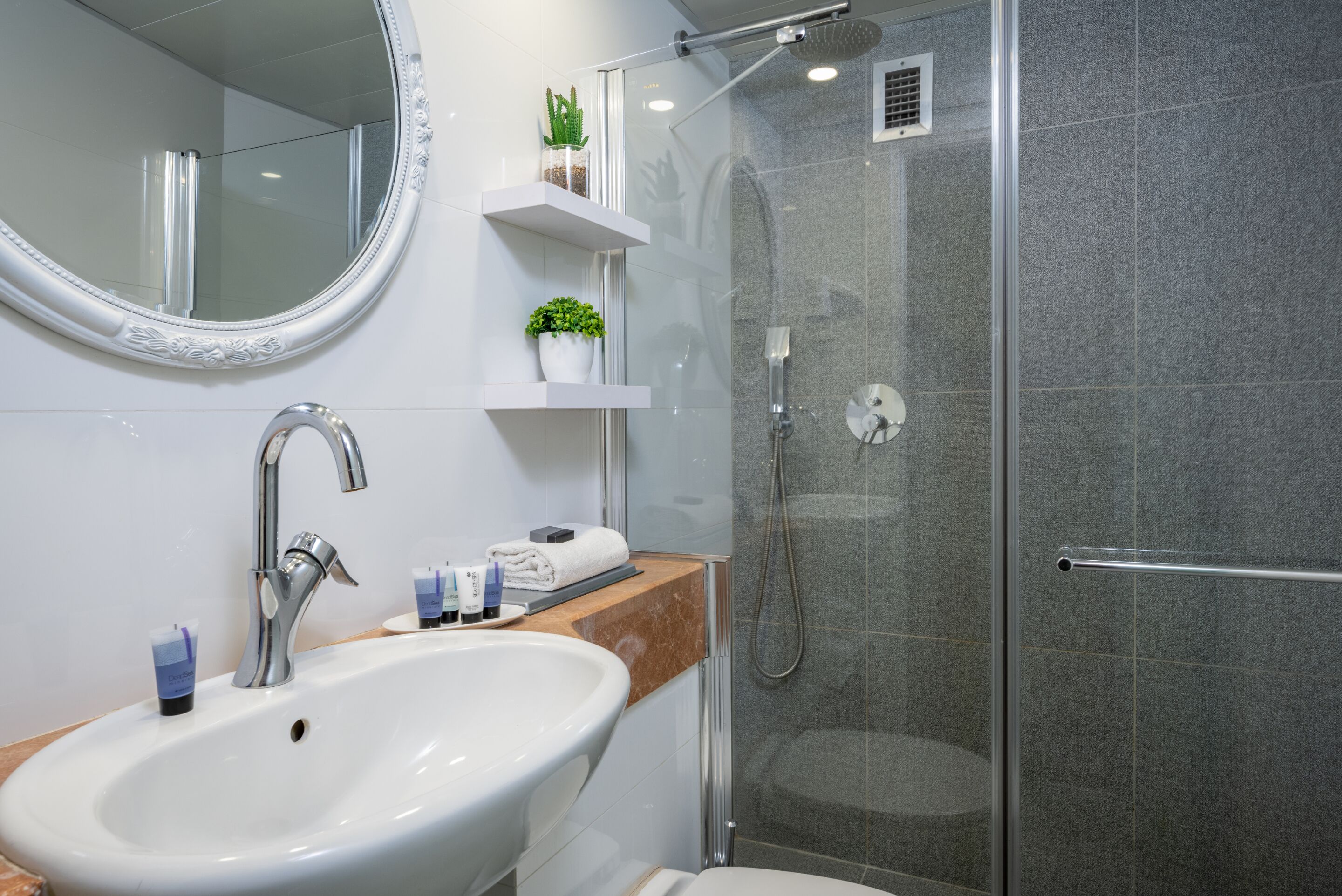 A modern bathroom with a white sink, mirror, and shower.