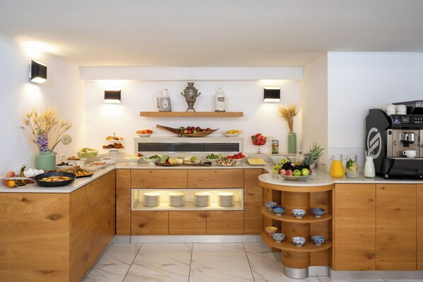 A modern kitchen with wooden cabinets, a built-in coffee station, and various food items displayed on the counter. - Maxim Hotel Tel Aviv (Tel Aviv)