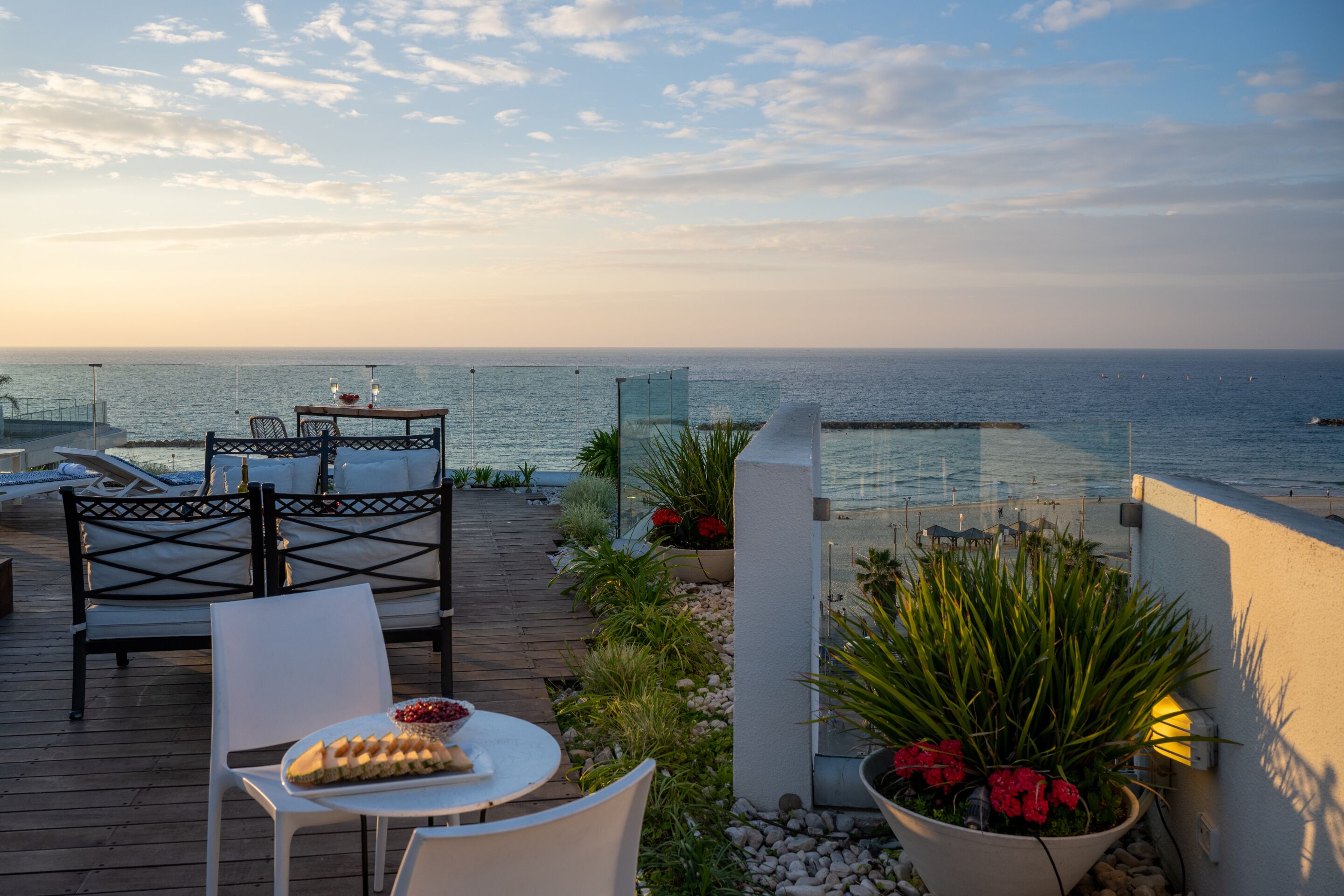 A deck with outdoor seating and a view of the sea.