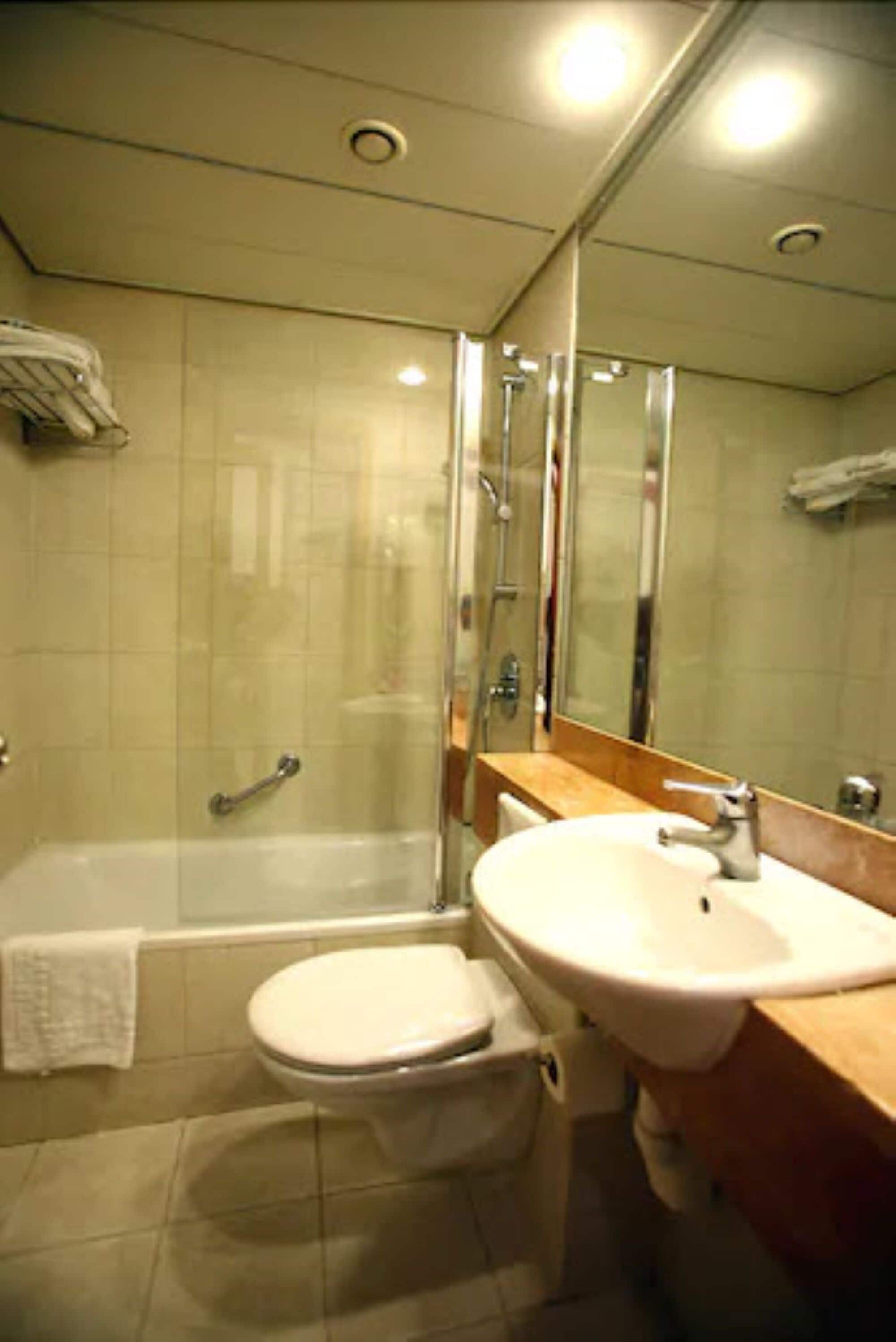 A bathroom with a bathtub, toilet, sink, and a glass-enclosed shower area.