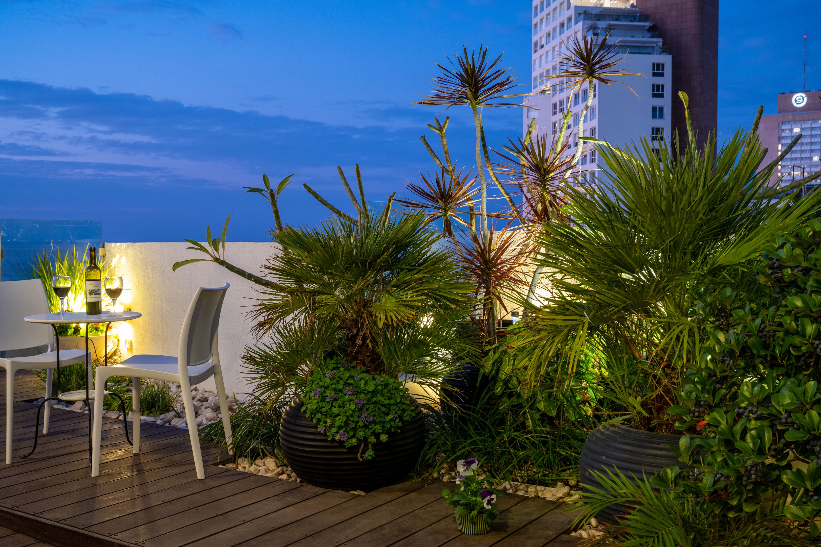 Une terrasse avec des sièges extérieurs et des plantes en pot, offrant une vue sur le paysage urbain.