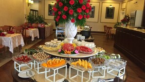 A buffet setup with various food items, a large floral centerpiece, and a dining area with tables and chairs. - Sammy Dalat Hotel (Xuan Huong - Da Lat)
