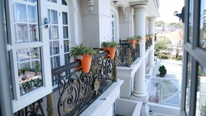 A balcony with white columns, ornate black railings, and potted plants. - Sammy Dalat Hotel (Xuan Huong - Da Lat)
