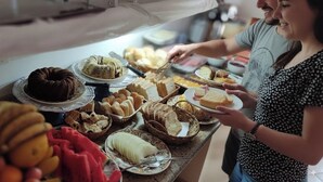 A buffet table with various food items including cakes, bread, and fruits.