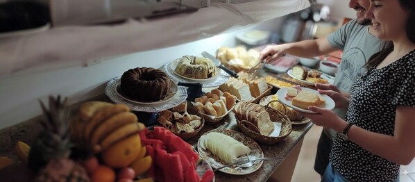 A buffet table with various food items including cakes, bread, and fruits. - Hotel Pousada Iracemar - Piscina Aquecida (Guarujá)