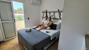 A bedroom with a bed, a window, and a balcony.