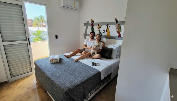 Een slaapkamer met een bed, een raam en een balkon.