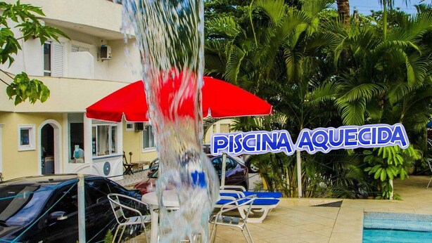 A swimming pool area with a sign reading "Piscina Aquecida" and a red umbrella.