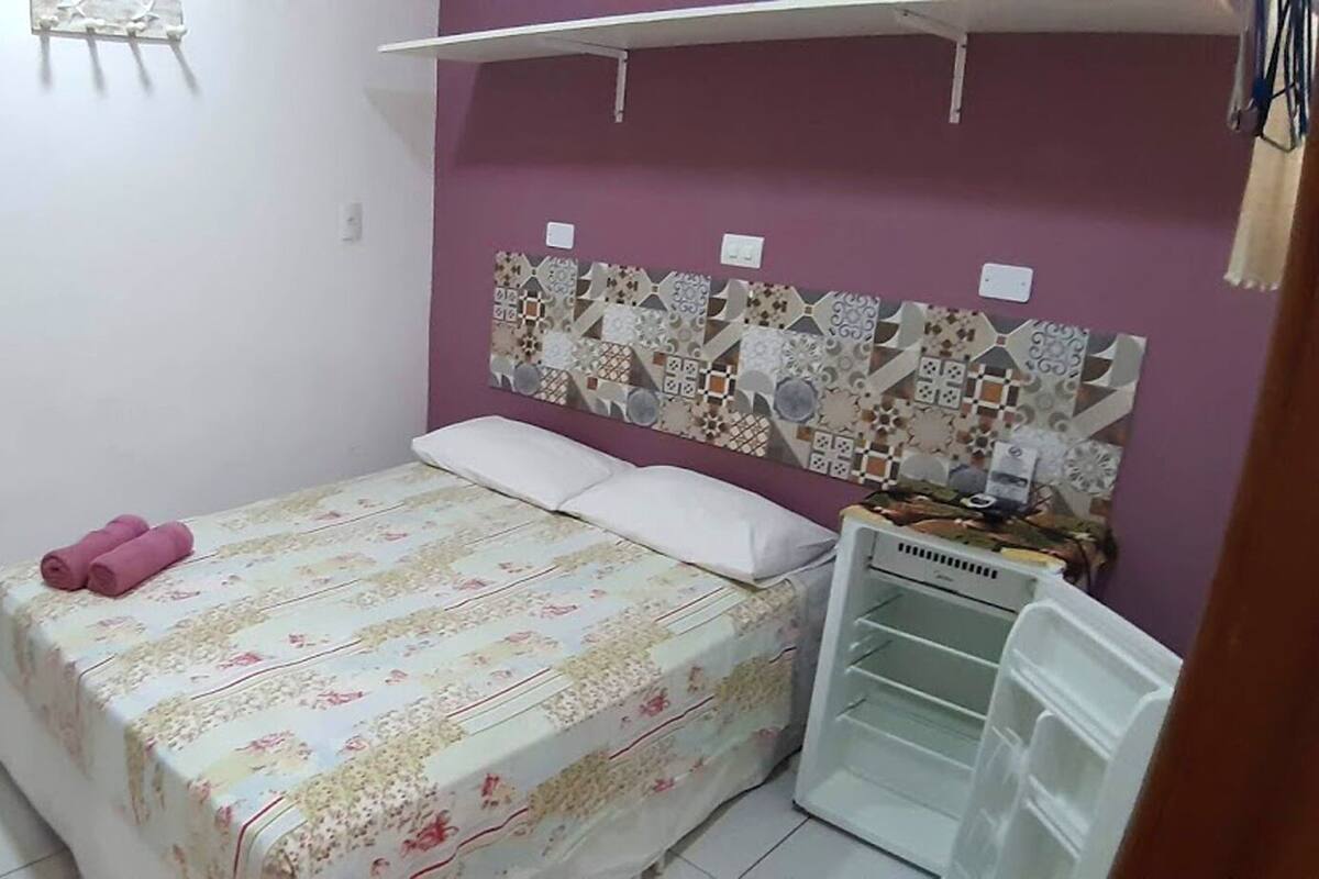 Une chambre à coucher comprenant un lit, une commode, un miroir et un mur recouvert de carreaux décoratifs.