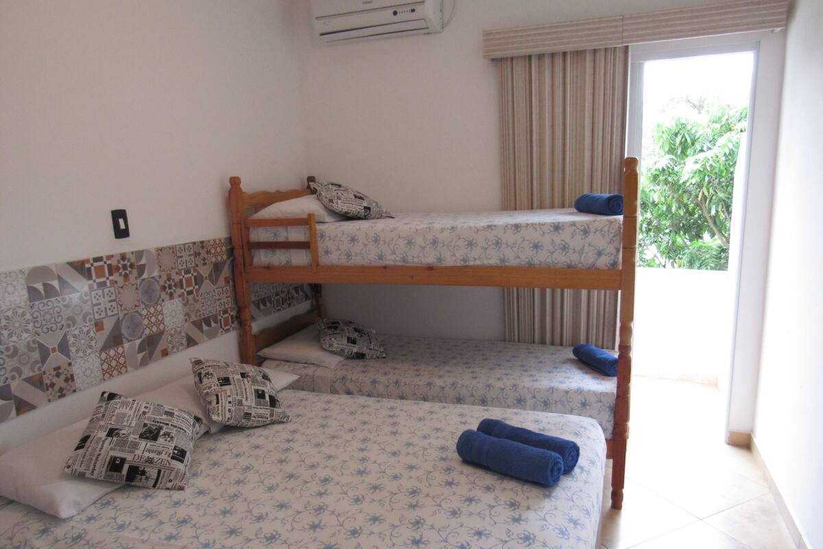 Une chambre avec des lits superposés, dotée de draps à motifs et offrant une vue sur la verdure environnante.