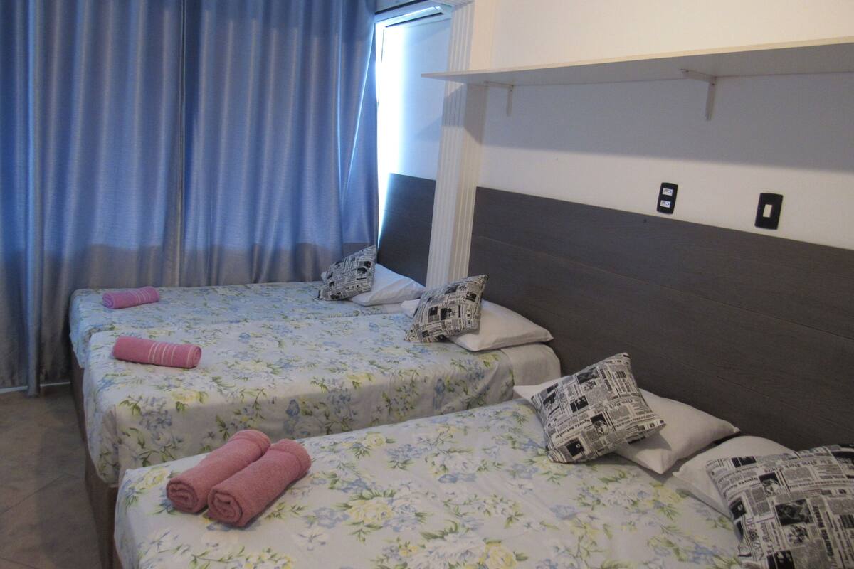 Une chambre d’hôtel avec deux lits, des couvre-lits à motifs floraux et des serviettes enroulées.