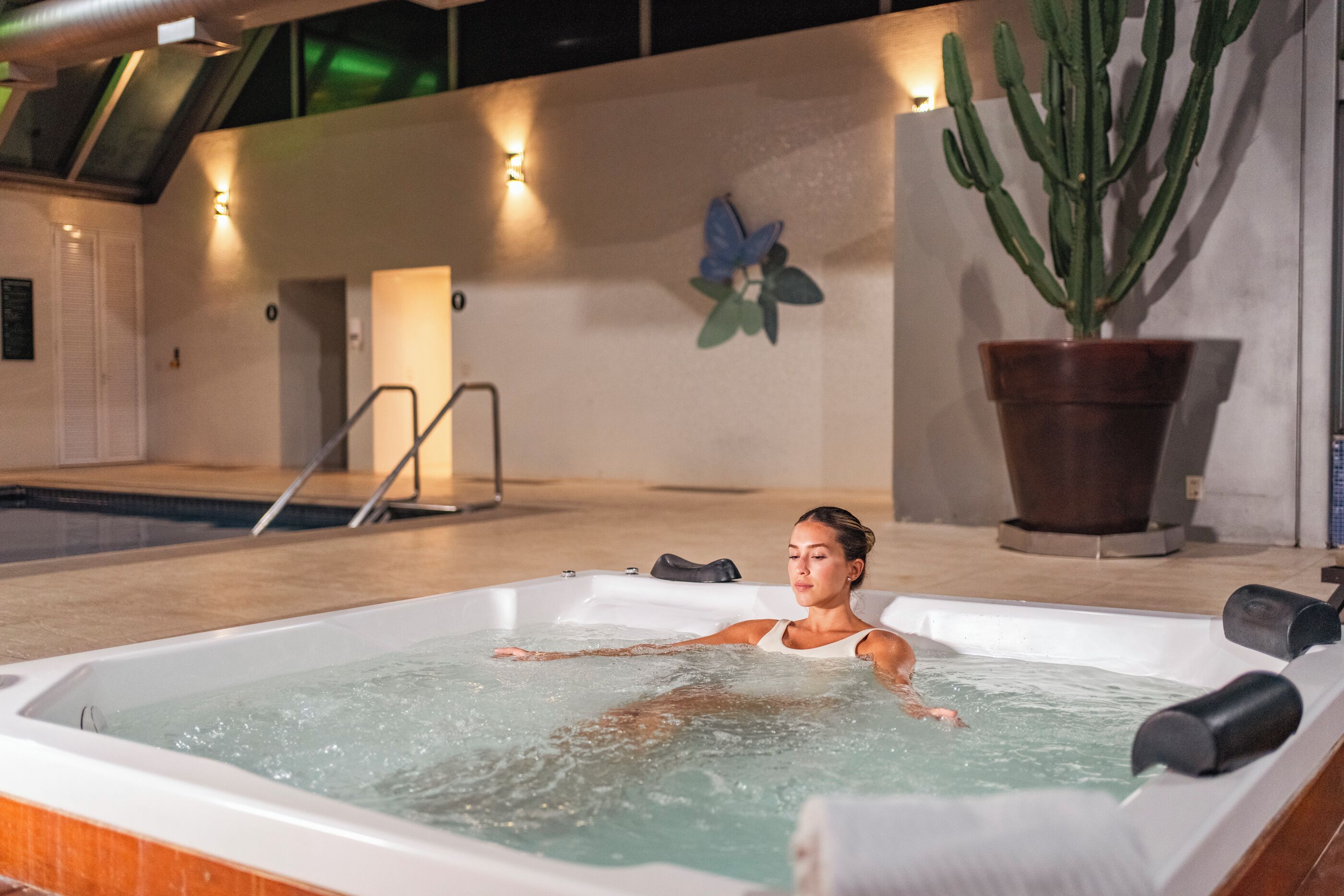 A spa area with a hot tub, a pool, and a large potted plant.