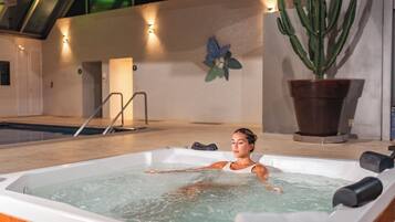 A spa area with a hot tub, a pool, and a large potted plant.